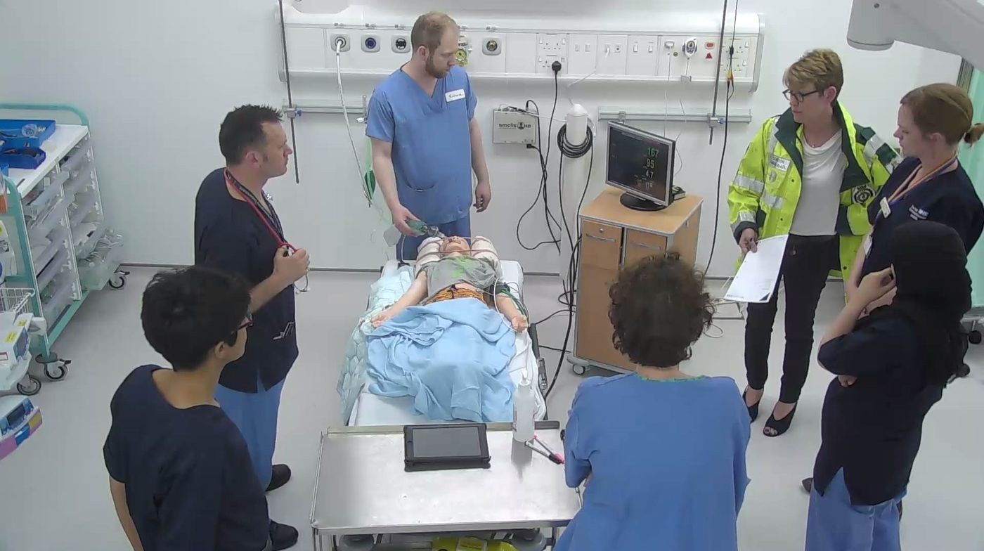Trauma team including a paramedic gathered around a child manikin during a simulation